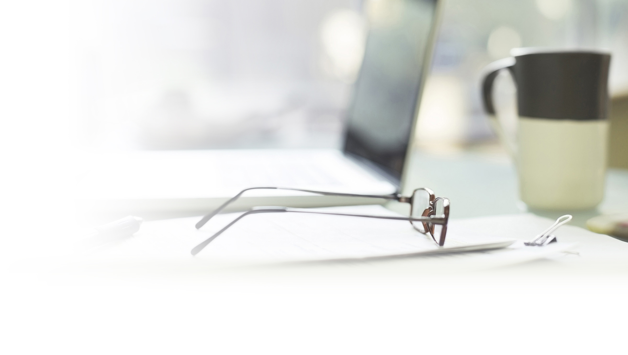 Pair of glasses on a desk next to a laptop